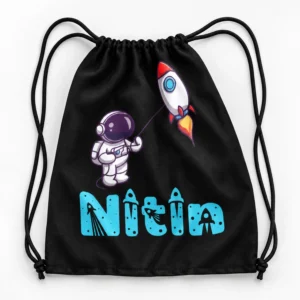 Flat-lay view of a black personalized kids drawstring bag with black cords, astronaut rocket artwork and the name Nitin in turquoise.