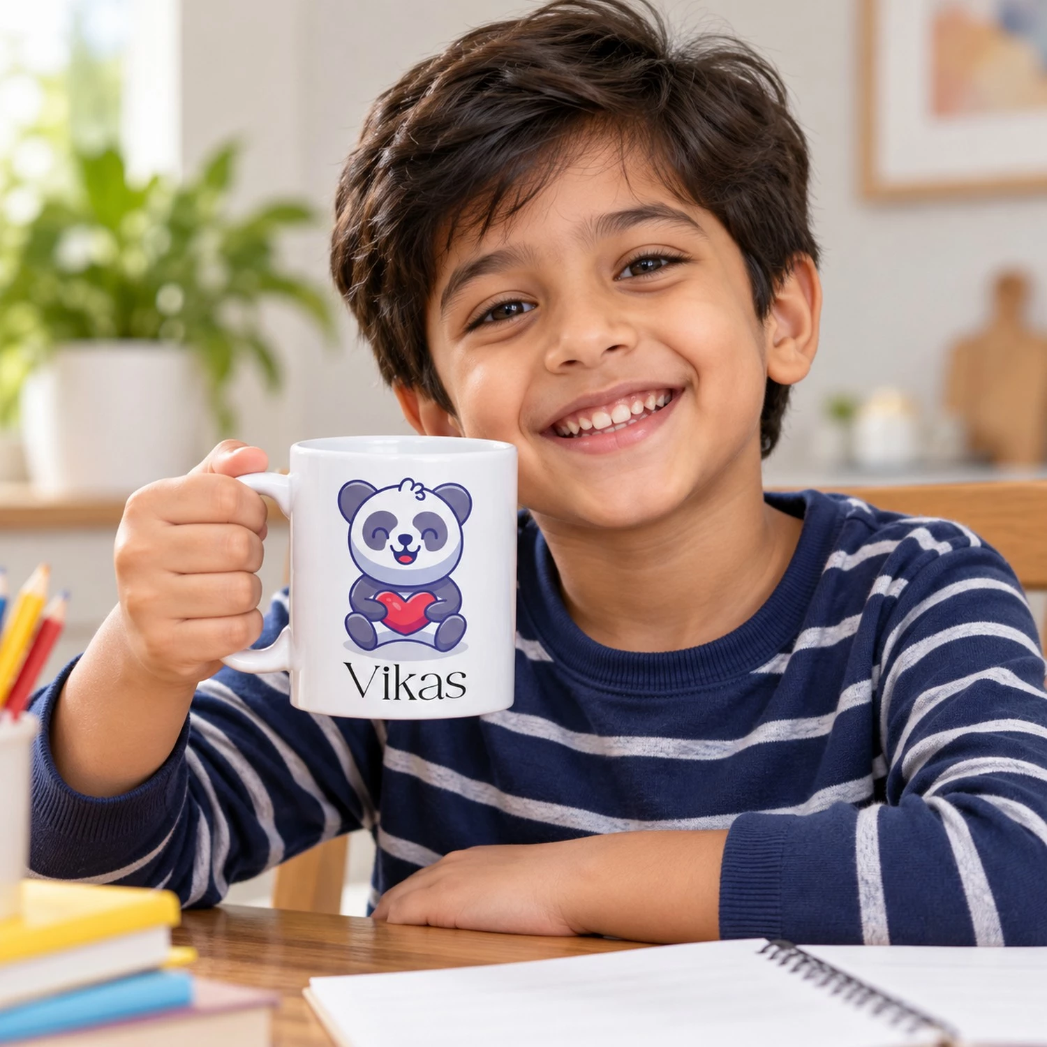 Smiling young boy holding a personalized white panda mug with a red heart design and the name Vikas.