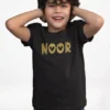 Child wearing black cotton T shirt with customized Noor name printed in gold design