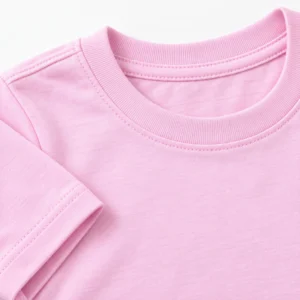 Close-up of pastel pink kids t-shirt fabric showing ribbed neckline, stitching, sleeve hem, and cotton texture