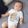 Baby wearing a 4th month birthday milestone onesie with a cute teddy bear design while lying on a bed