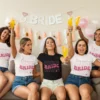 Group of women wearing matching Team Bride t-shirts celebrating a bachelorette party with drinks and decorations