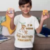 Boy wearing a white big brother announcement T-shirt with cute monkey design holding toys, perfect for pregnancy reveal