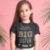 Young girl wearing a black Big Sister 2026 pregnancy announcement t-shirt with leopard print text on a pink background
