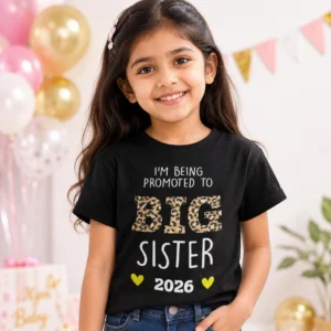 Young girl wearing a black Big Sister 2026 pregnancy announcement t-shirt with leopard print text on a pink background