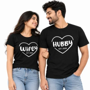 Couple wearing matching black WIFEY and HUBBY T-shirts featuring white heart outlines, bold white lettering, and EST. 2026 details.