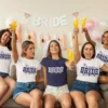 Bride and friends wearing matching bride and team bride t shirts celebrating bachelorette party with drinks and decorations