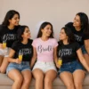 Bride in a pink Bride T-shirt and veil surrounded by friends wearing matching black Team Bride T-shirts