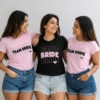 Bride wearing a black Bride T-shirt with friends in matching pink Team Bride T-shirts for a bachelorette celebration