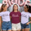Three women wearing matching bride and team bride t shirts at a bachelorette party celebration with decorative backdrop