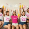 Group of women wearing matching Bride Tribe t-shirts celebrating a bachelorette party with drinks and decorations