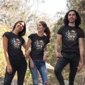 Three people wearing black Cousin Crew 2026 matching T-shirts with colorful summer design during a family trip outdoors