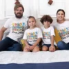Family of four wearing matching Goa vacation themed T-shirts with colorful beach design sitting together