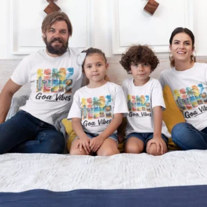 Family of four wearing matching Goa vacation themed T-shirts with colorful beach design sitting together