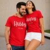 Husband and wife wearing matching red Hubby and Wifey Est. 2026 couple T-shirts with simple white lettering