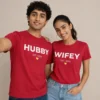 Couple wearing matching red Hubby and Wifey Est. 2026 T-shirts with bold white lettering and yellow heart detail