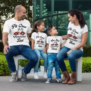 Family wearing personalized pit crew matching t-shirts with names and racing theme design, sitting together outdoors and smiling