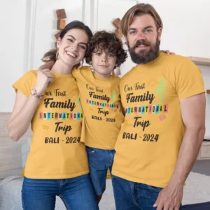 Family of three wearing matching personalized yellow T-shirts with “Our First Family International Trip Bali 2024” design