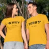 Couple wearing matching yellow Hubby and Wifey T-shirts with customized EST year, holding hands outdoors