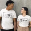 Couple wearing matching personalized hubby and wifey t-shirts with custom est year printed in minimal typography design