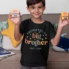 Boy wearing a black promoted to big brother t-shirt holding toys, ideal for pregnancy announcement photoshoot