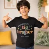 Boy wearing a black promoted to big brother t-shirt holding toys, ideal for pregnancy announcement photoshoot