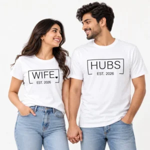 Couple wearing matching white T-shirts with black WIFE and HUBS typography, outlined rectangular designs, small heart detail, and EST. 2026 prints.