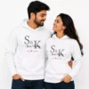 Couple wearing matching white personalized hoodies with custom initials, names, and anniversary year design.