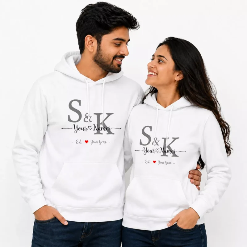 Couple wearing matching white personalized hoodies with custom initials, names, and anniversary year design.
