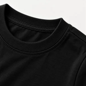 Close-up of a black kids t-shirt showing fabric texture, ribbed crew neckline, and shoulder stitching.