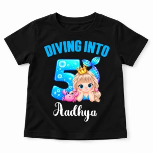 Flat-lay view of a black personalized kids birthday t-shirt with a mermaid-themed "Diving Into 5" print and the name Aadhya on a white background.