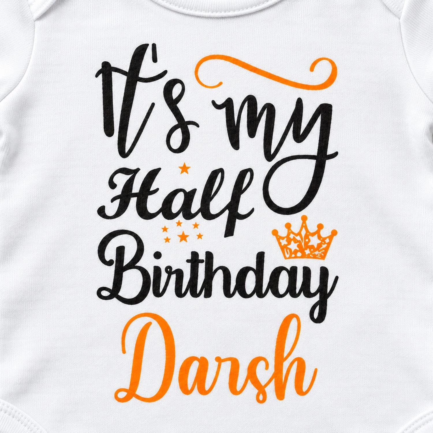 Close-up of the personalized half birthday baby romper print with “It’s my Half Birthday Darsh” lettering, orange stars and crown.