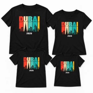 Flat-lay of matching family vacation T-shirts in black with Dubai 2026 skyline prints arranged in adult and kids sizes.