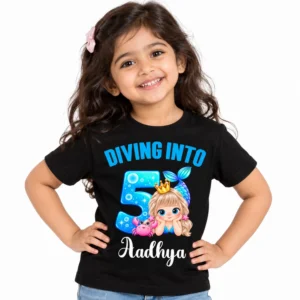 Indian child wearing a black personalized 5th birthday kids t-shirt with a blue mermaid design, "Diving Into 5" text, and the name Aadhya on a light studio background.