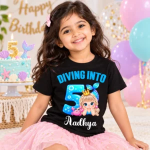 Child wearing a black personalized 5th birthday mermaid t-shirt with the name Aadhya in a birthday setting with balloons and a cake.
