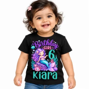 Indian toddler wearing a black personalized birthday girl kids t-shirt with a colorful mermaid design, number 6, and the name Kiara on a white background.
