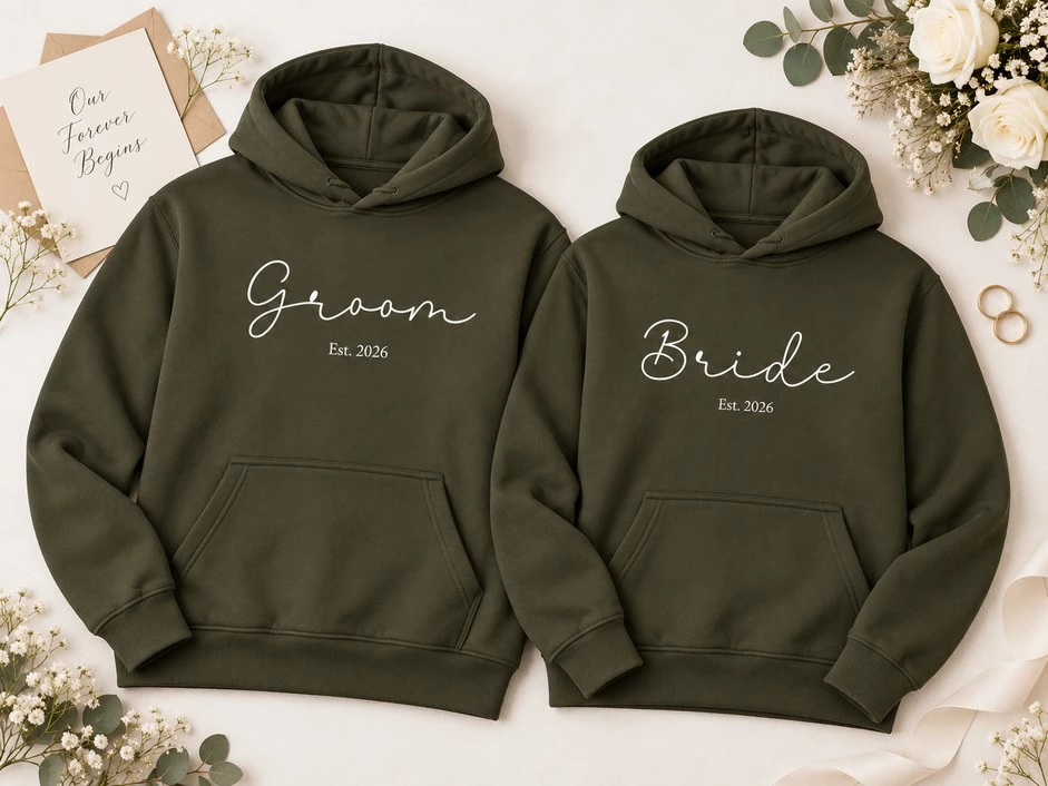 Olive-green matching Bride and Groom hoodies featuring white script lettering and personalized Est. 2026 wedding year designs.