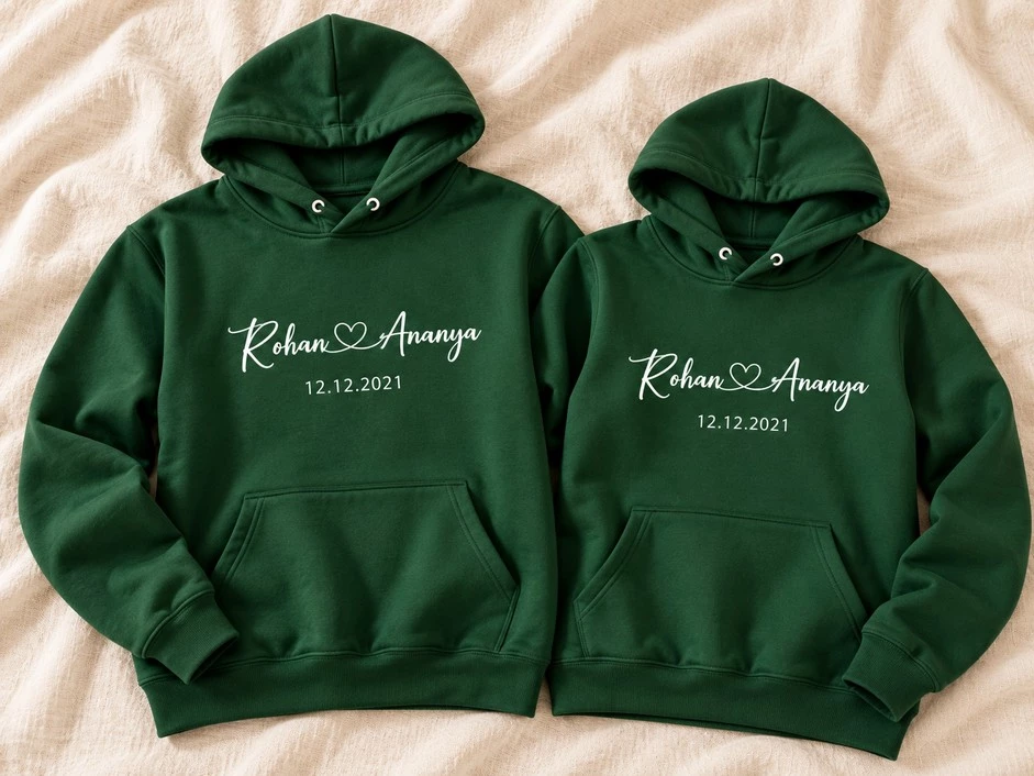 Matching forest green couple hoodies personalized with Rohan and Ananya's names and the special date 12.12.2021.