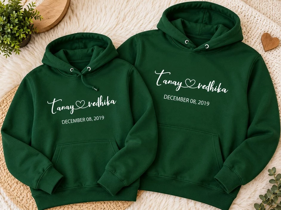 Two forest green personalized couple hoodies featuring Tanay and Vedhika names with a heart and December 08, 2019 date.