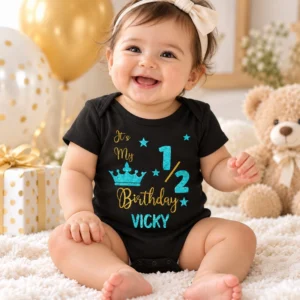 Baby wearing a black personalized VICKY half birthday romper in a birthday celebration setting with balloons, gift box and teddy bear.