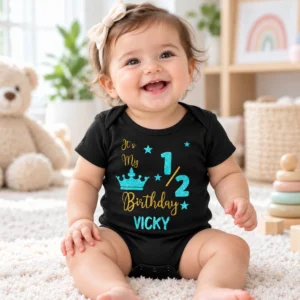 Smiling baby wearing a black personalized VICKY half birthday romper in a bright nursery with a teddy bear and baby toys.