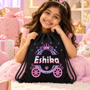 Smiling Indian girl holding a black personalized Eshika kids drawstring bag in a pink princess-themed birthday gift setting.