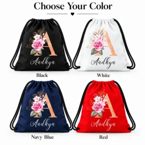 Four personalized kids drawstring bags in black, white, navy blue, and red with black cords, floral letter A artwork, and the name Aadhya.