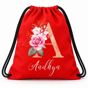 Red personalized kids drawstring bag with black cords, a glittery floral letter A design, and the name Aadhya in white script.