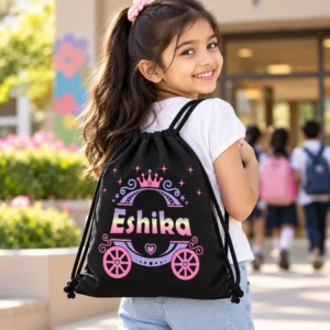 Indian school-age girl wearing a black personalized Eshika drawstring bag with pink princess carriage design outside a school.