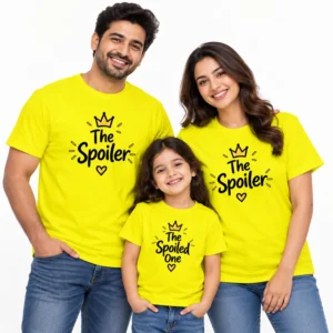 Family of three wearing bright yellow matching family T-shirts with black crown and heart designs, featuring The Spoiler on both adult shirts and The Spoiled One on the child's T-shirt.